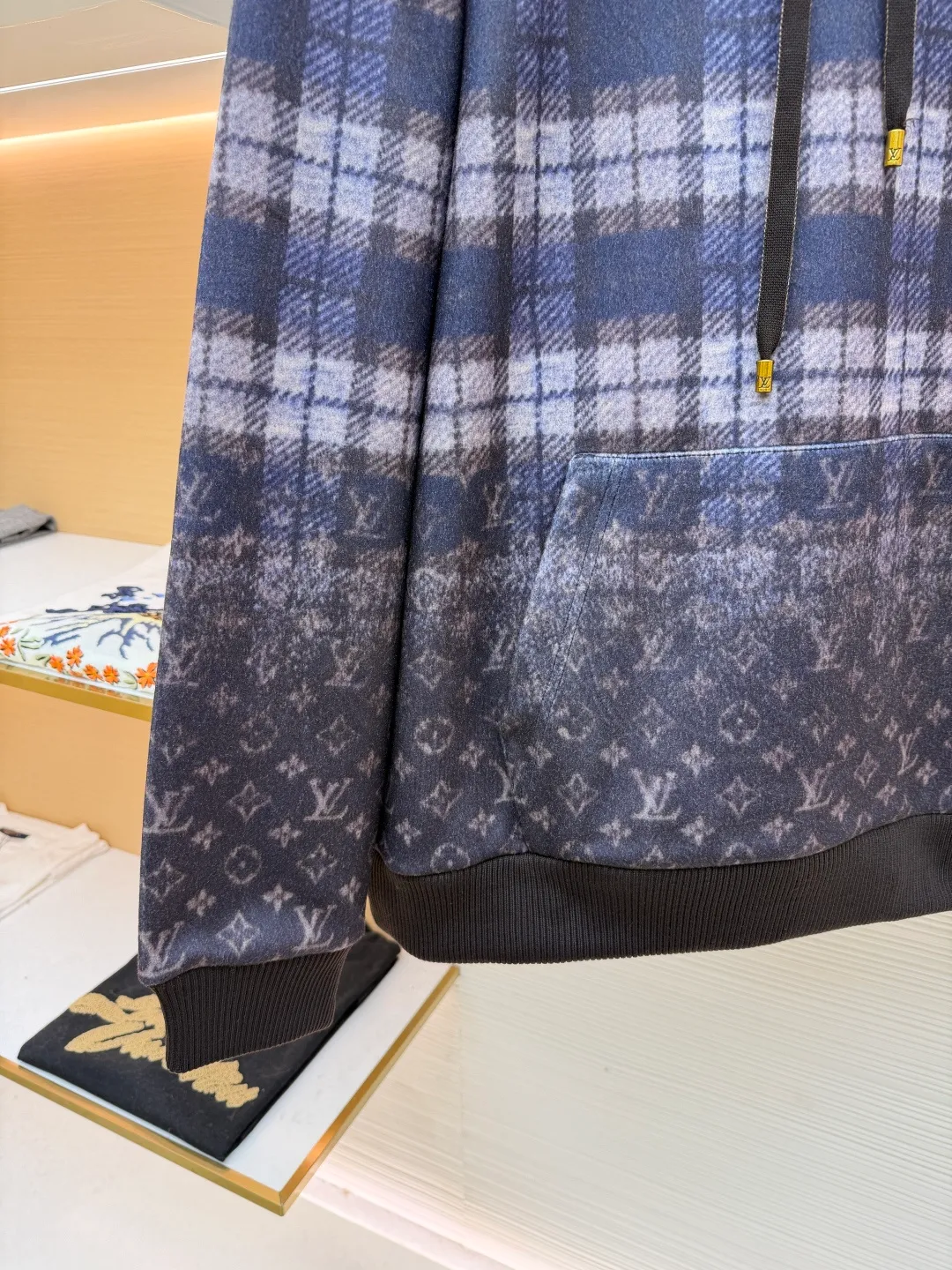 LOUIS VUITTON plaid gradient long-sleeved hoodie ●Original version: Purchased and developed for 15100 ●Item number: 1681896-B40 ●Fabric: wool blended fabric ●Technology: Digital direct printing ●Color: Purple ●Version: Fitted version ●Weight: about 1035 grams ●Size: S-M-L-XL ●Description: This hooded sweatshirt uses splicing technology to create a layered texture: the upper part is made of wool blended fabric with a blue and gray plaid pattern, and is pre-shrunk to ensure a stable fit; the lower part and sleeves use digital printing technology to present a gradient Monogram dark pattern, and the ink penetrates the fiber to achieve high color fastness. The hood has a built-in invisible lining to enhance stiffness, and the drawstring is made of wear-resistant nylon rope with a metal bell for smooth pulling. The front kangaroo pocket is made of welted bag technology, and the edge of the bag mouth is reinforced with double stitching. The cuffs and hem are made of ribbed knitted fabric, and the elastic hemming fits the body shape. The seams throughout the garment are high-strength stitches of the same color. Precision sewing every 3cm/12 stitches improves durability. The overall craftsmanship takes into account both visual details and practical durability. The overall wiring is straight and delicate, the fabric is comfortable and soft, and the color is consistent without color difference. It can be matched with the same style to create a fashionable look and control various occasions. Customized accessories, complete with three standards, same style for men and women!